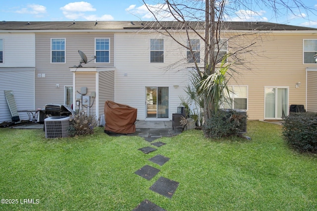 rear view of property with cooling unit and a yard