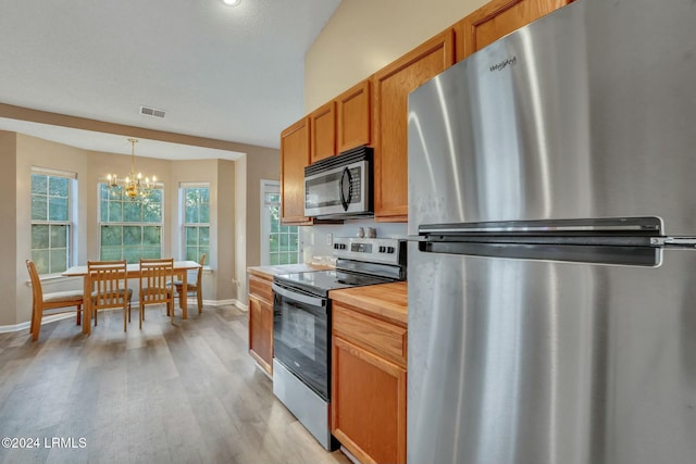 kitchen featuring stainless steel appliances, a chandelier, light hardwood / wood-style floors, and hanging light fixtures