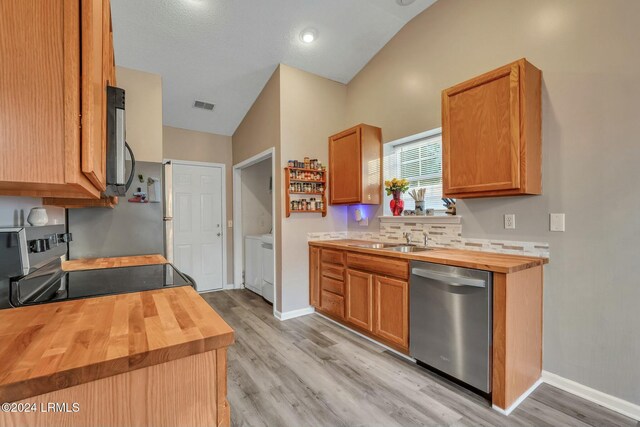 kitchen with stainless steel appliances, sink, wooden counters, and light hardwood / wood-style flooring