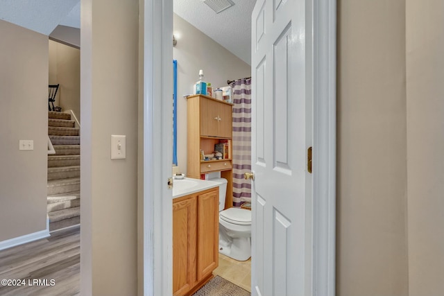 bathroom with vanity, toilet, wood-type flooring, and a textured ceiling