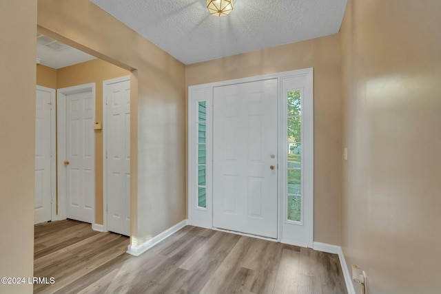 foyer with light wood-type flooring and a textured ceiling