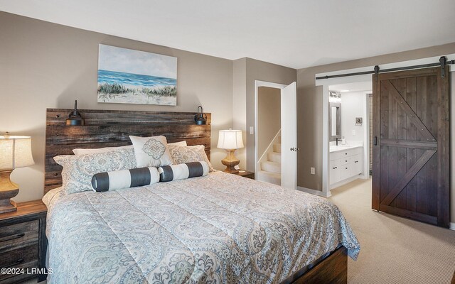 carpeted bedroom featuring ensuite bathroom and a barn door