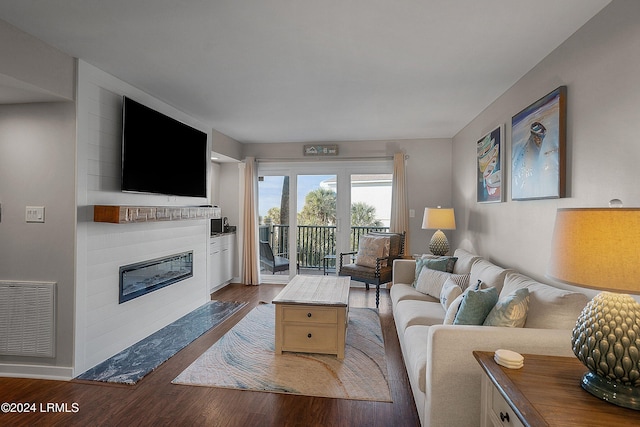 living room with a large fireplace and dark hardwood / wood-style flooring