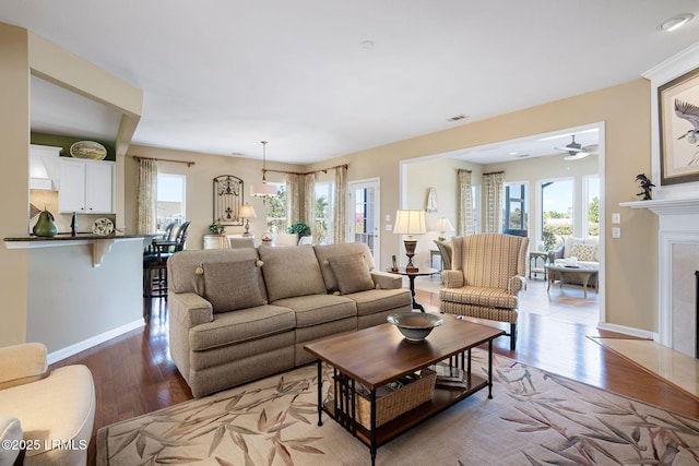 living area featuring light wood-type flooring, a fireplace with flush hearth, visible vents, and a healthy amount of sunlight