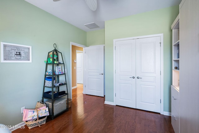 bedroom with a closet, dark wood finished floors, visible vents, and baseboards