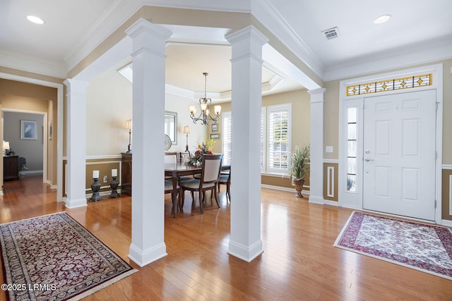 entryway featuring crown molding, light wood-style floors, visible vents, and ornate columns