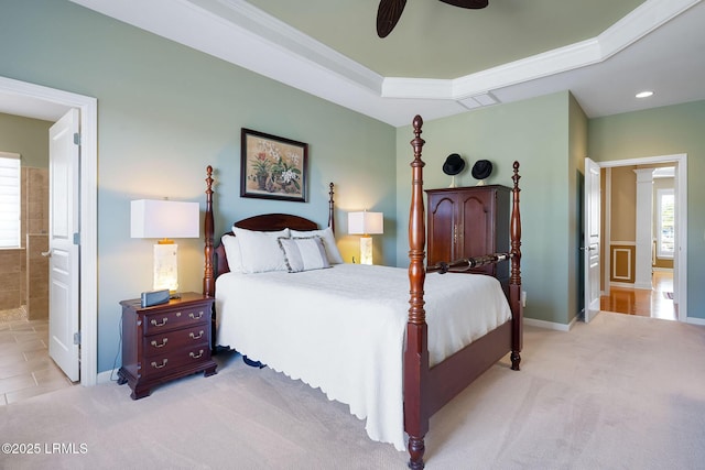 bedroom with light carpet, baseboards, visible vents, a raised ceiling, and ensuite bathroom