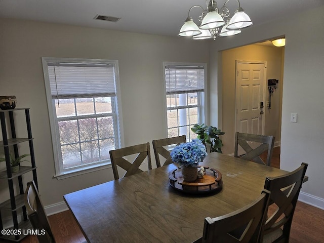 dining space featuring dark wood-type flooring and an inviting chandelier