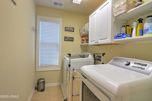 clothes washing area with cabinets and washer and clothes dryer