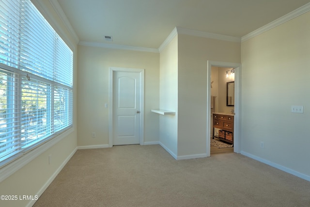 unfurnished bedroom with multiple windows, ensuite bathroom, light colored carpet, and crown molding