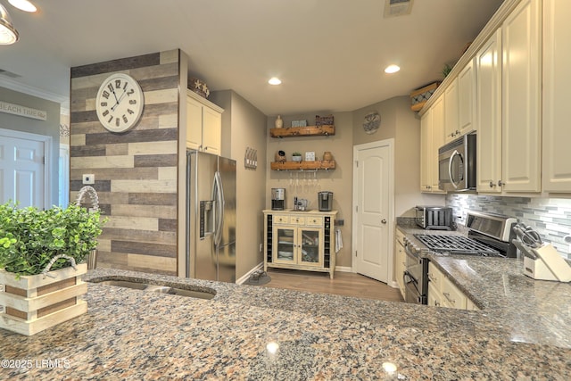 kitchen featuring appliances with stainless steel finishes, sink, dark stone countertops, backsplash, and ornamental molding