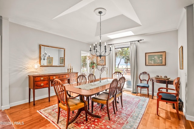 207 Odingsell Ct, Saint Helena Island, SC 29920 - dining room featuring a chandelier, a skylight, light wood-style flooring, crown molding, and baseboards