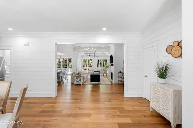 interior space with wooden walls, a notable chandelier, light wood finished floors, recessed lighting, and ornamental molding