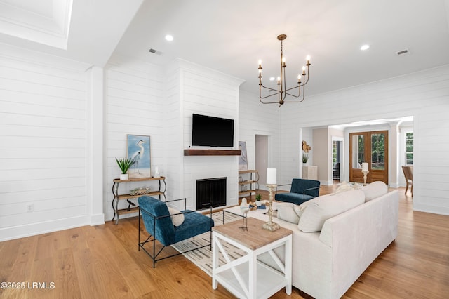 living room featuring a notable chandelier, a fireplace, light wood-style flooring, baseboards, and visible vents
