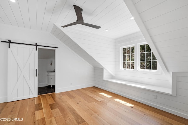 additional living space featuring ceiling fan, a barn door, wooden ceiling, baseboards, and light wood-style flooring