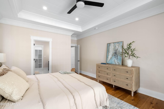 bedroom with recessed lighting, a tray ceiling, ornamental molding, and wood finished floors