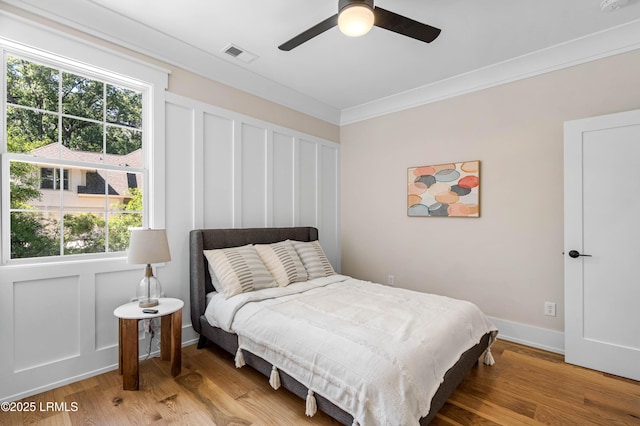 bedroom featuring visible vents, ornamental molding, light wood finished floors, and a ceiling fan