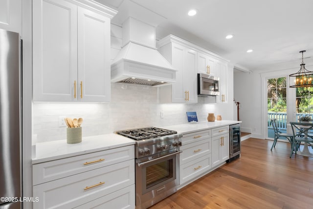 kitchen with appliances with stainless steel finishes, tasteful backsplash, custom exhaust hood, beverage cooler, and light wood-style flooring