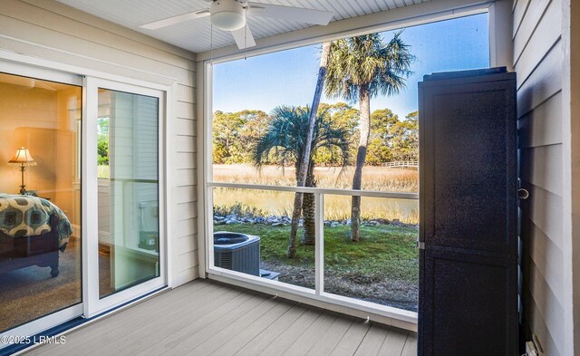 unfurnished sunroom with ceiling fan and a water view