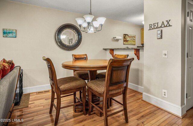 dining room with light hardwood / wood-style flooring and a chandelier