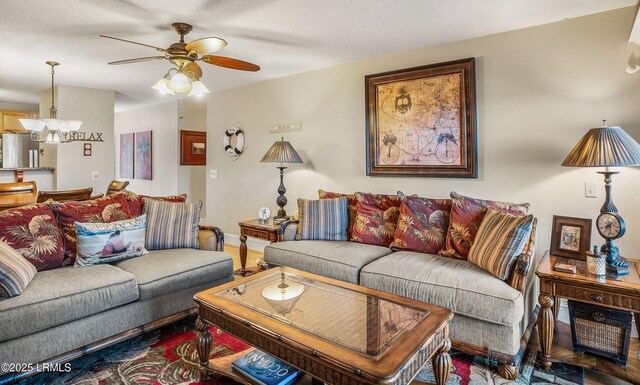 living room with ceiling fan with notable chandelier and a textured ceiling