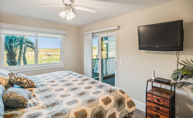 bedroom with ceiling fan, access to exterior, and a textured ceiling