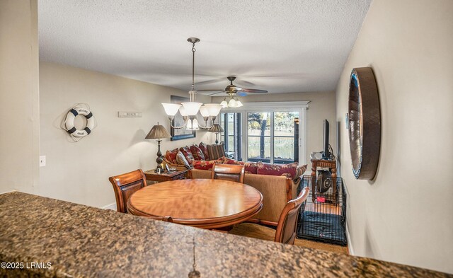 dining room with ceiling fan with notable chandelier and a textured ceiling