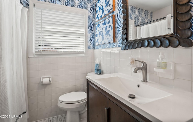 bathroom featuring vanity, toilet, and tile walls