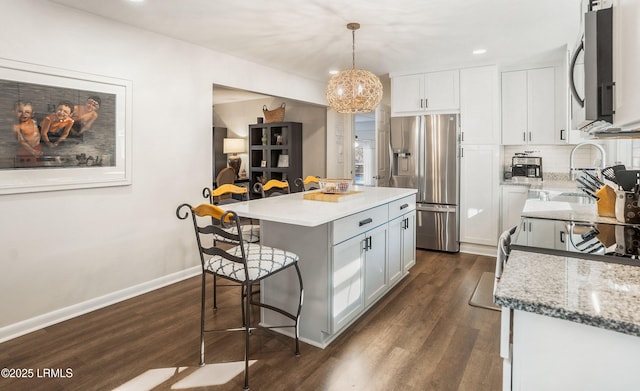 kitchen featuring pendant lighting, white cabinetry, backsplash, a center island, and stainless steel appliances