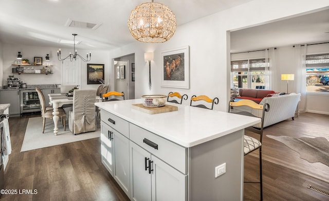 kitchen with wine cooler, a kitchen bar, an inviting chandelier, hanging light fixtures, and a kitchen island