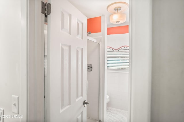 interior details featuring toilet and a tile shower