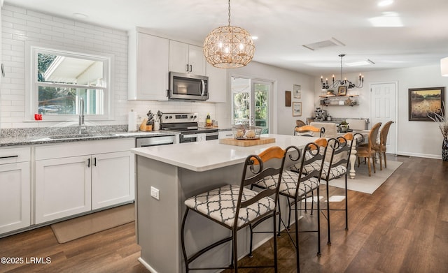 kitchen with appliances with stainless steel finishes, decorative light fixtures, sink, and white cabinets