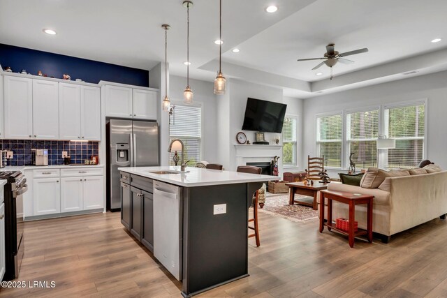 living room featuring a raised ceiling, ceiling fan, and light wood-type flooring