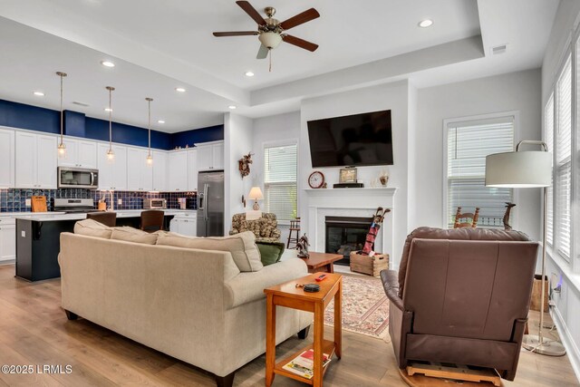 kitchen with a kitchen island with sink, pendant lighting, white cabinets, and appliances with stainless steel finishes