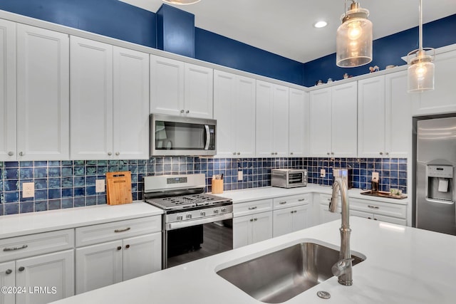 kitchen with sink, white cabinetry, hanging light fixtures, appliances with stainless steel finishes, and backsplash