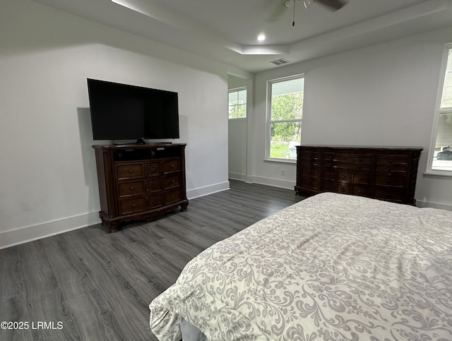 bedroom featuring dark wood-style floors, a raised ceiling, visible vents, and baseboards