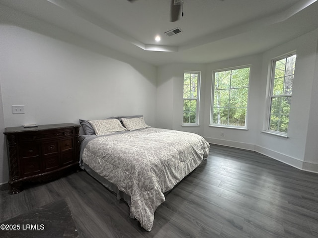 bedroom with dark wood finished floors, recessed lighting, a raised ceiling, visible vents, and baseboards