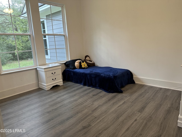 bedroom with dark wood-style floors and baseboards