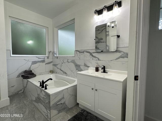 bathroom with a garden tub, tile walls, and vanity