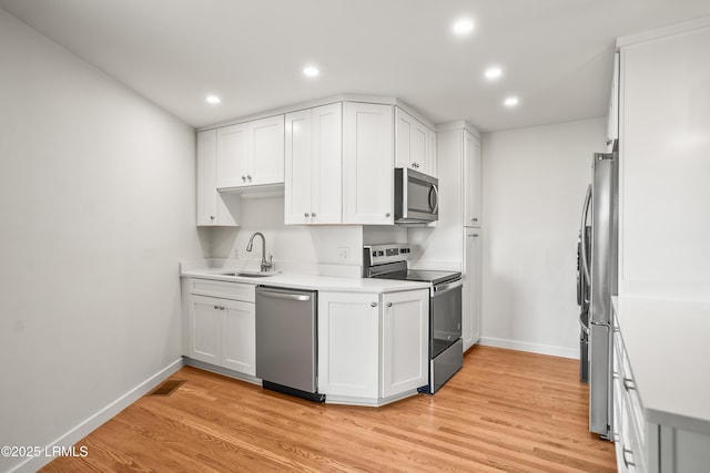 1203 Laudonniere St, Beaufort, SC 29902 - kitchen with stainless steel appliances, white cabinets, recessed lighting, light wood-style floors, and light countertops
