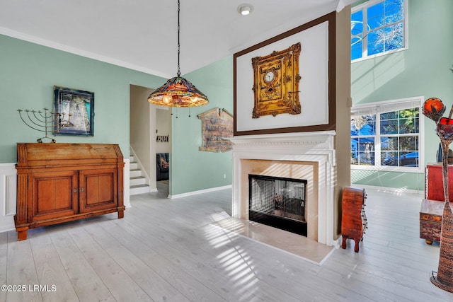 living room featuring crown molding, a high end fireplace, and light wood-type flooring