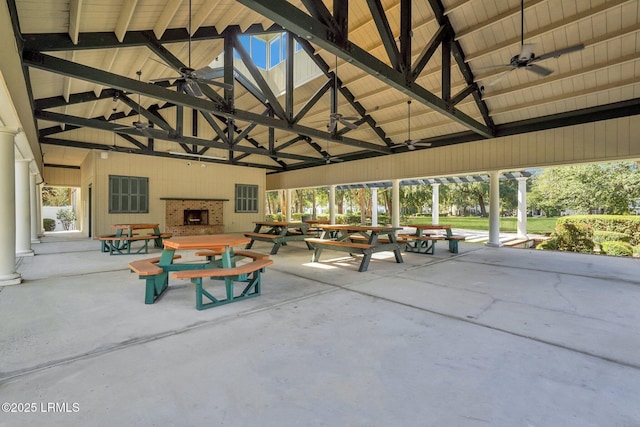 view of patio featuring an outdoor brick fireplace, a gazebo, and ceiling fan