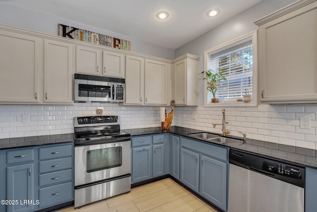 kitchen with stainless steel appliances, blue cabinets, sink, and backsplash