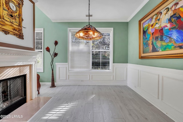 dining room featuring crown molding, a fireplace, and light wood-type flooring