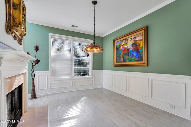 unfurnished dining area with crown molding, light hardwood / wood-style floors, and a premium fireplace