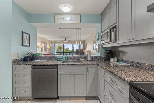 kitchen with sink, dark stone countertops, light tile patterned floors, appliances with stainless steel finishes, and gray cabinets