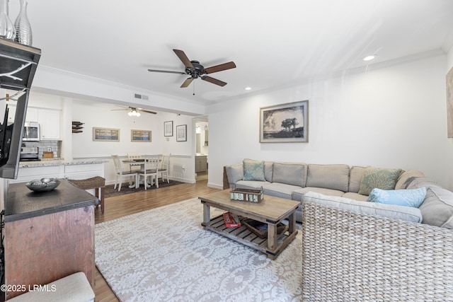 living area with crown molding, recessed lighting, visible vents, a ceiling fan, and wood finished floors