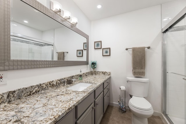 full bathroom featuring a stall shower, baseboards, vanity, and toilet