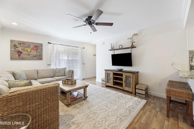 living area with light wood-style flooring, baseboards, ceiling fan, and ornamental molding