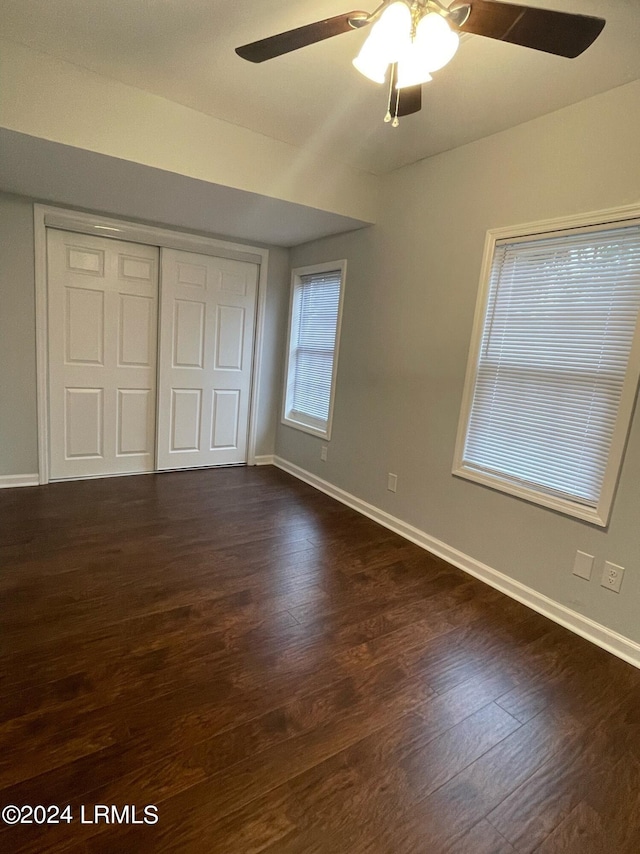 unfurnished bedroom featuring a closet, dark hardwood / wood-style floors, and ceiling fan